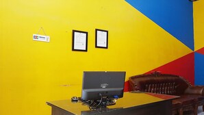 Un mostrador de recepción con una computadora, dos certificados enmarcados en la pared y un sofá de cuero marrón.