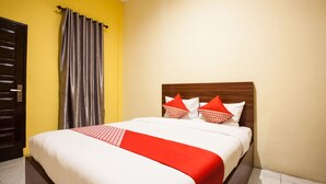 Una cama bien hecha con una colcha blanca y roja, dos almohadas con diseños rojo y blanco, y un cabecero de madera.
