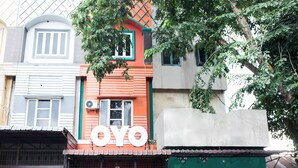 Un edificio con un llamativo letrero 'OYO', que presenta una fachada tradicional con techo de tejas y una entrada amplia.