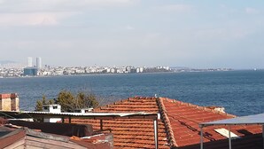 A coastal cityscape with a view of the sea, buildings, and a distant lighthouse.