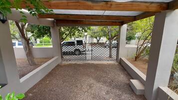 A covered outdoor area with a gravel floor, surrounded by concrete pillars and a metal fence.