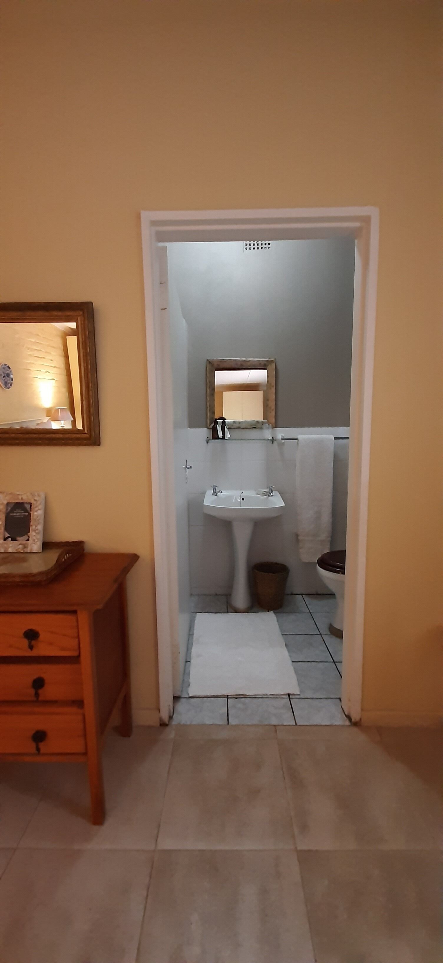 Un baño con lavabo, inodoro y un armario de madera con cajones.