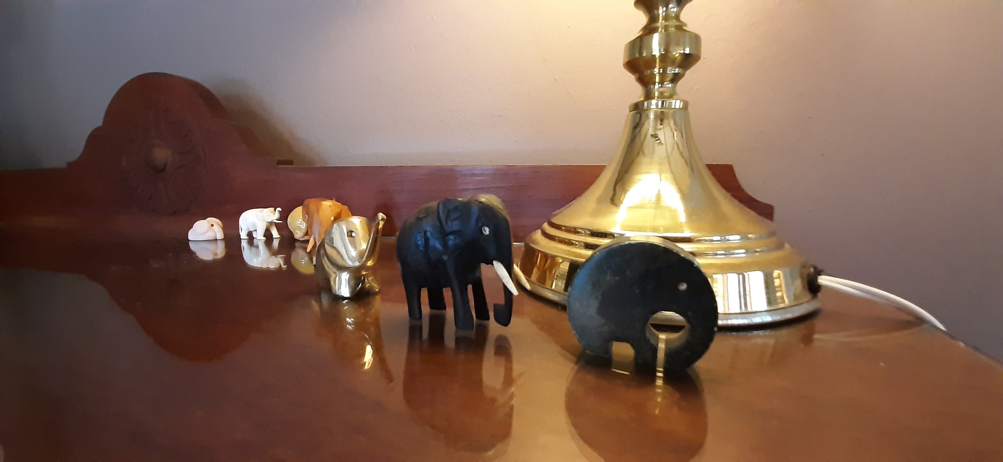 Ein Holztisch mit einer Messinglampe, einem schwarzen Gegenstand und mehreren kleinen Figuren.