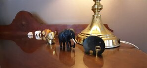 A wooden table with a brass lamp, a black object, and several small figurines. - Abigails Garden Cottage (Montagu)