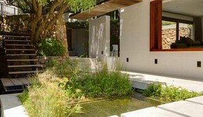 A modern building with a stone staircase, a small garden area with grass and plants, and a clear view of the sky. - Le Thallo (Cape Town)