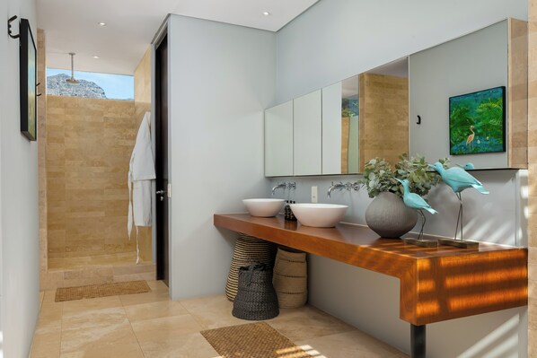 A modern bathroom with a large mirror, two sinks, and a shower area.