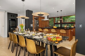 Una cocina moderna con una isla de mármol, armarios de madera y un amplio ventanal con vistas al verdor.