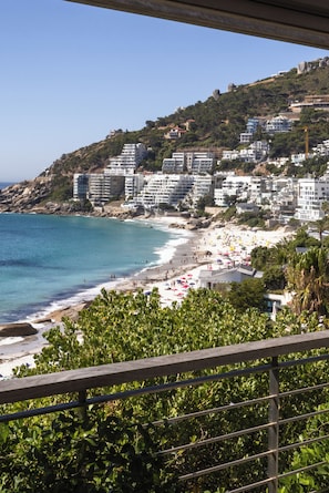 A coastal view with a beach, buildings, and greenery.
