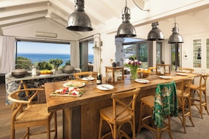 A spacious dining area with a large wooden table, multiple chairs, and pendant lighting.