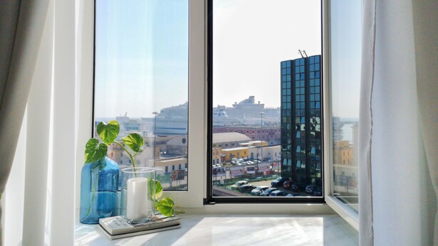 A window with a view of a cityscape, including a tall building and parked cars. - B&B Civico 13 (Naples)