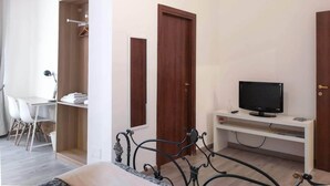A bedroom with a bed, a desk with a TV, a wardrobe, and a chair. - B&B Civico 13 (Naples)
