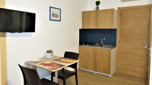 A compact kitchen with a dining table, chairs, a built-in stove, and a sink. - Residenza Montegrappa (Peschici)
