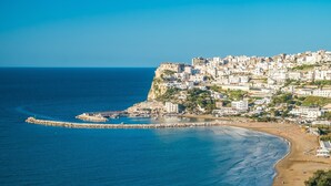 A coastal town with a prominent cliff, a pier, and a beach. - Residenza Montegrappa (Peschici)