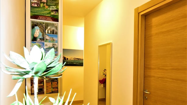 A hallway with a wooden door, a mirror, and a wall with informational posters. - Residenza Montegrappa (Peschici)