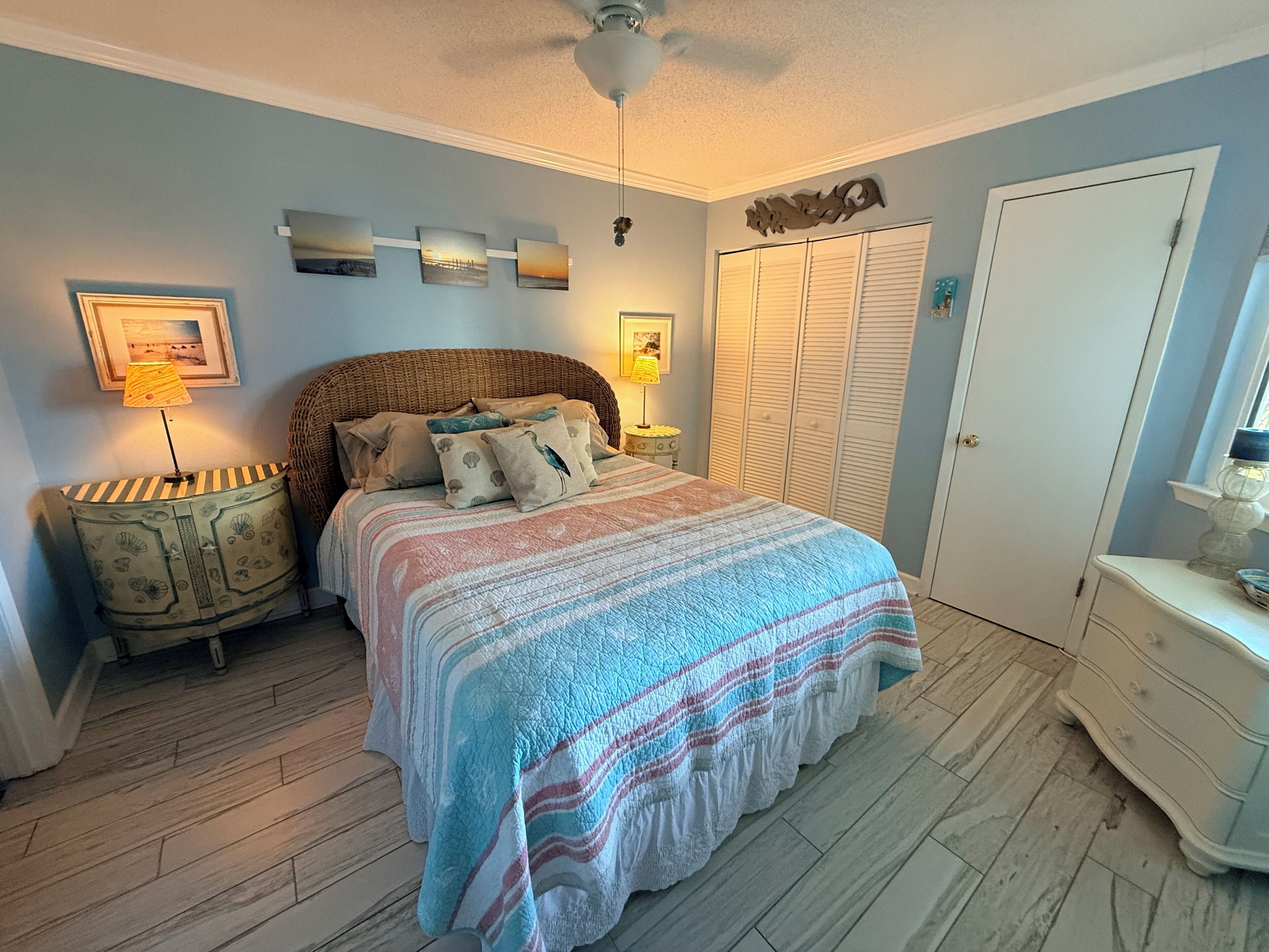 A bedroom with a bed, bedside tables, a wardrobe, and a ceiling fan.