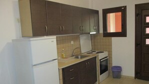 A compact kitchen with a refrigerator, stove, sink, and cabinets.