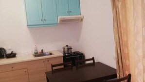 A compact kitchen with teal cabinets, a small dining table with four chairs, and a single stove.