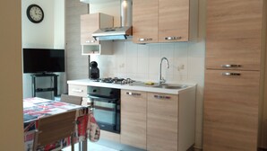 A modern kitchen with wooden cabinets, a built-in oven, a gas stove, a sink, and a stainless steel range hood. - Kibilù - Viale Bligny OSV (Milan)