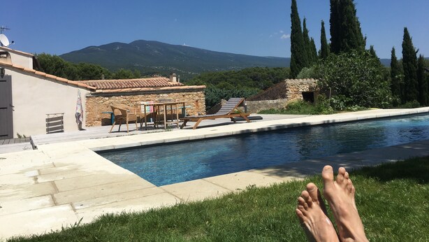 Un área junto a la piscina con sillones de descanso y un edificio de piedra.