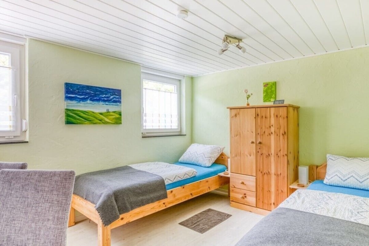 Ein Schlafzimmer mit zwei Einzelbetten, einem Holzschrank und einem Bild an der Wand.
