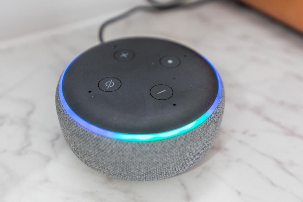 Un dispositivo smart con rivestimento in tessuto e un anello luminoso blu, appoggiato su una superficie in marmo.