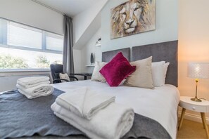 A hotel room with a bed, a desk, a chair, and a window with blinds. - West Bridgford Classy 2bed Flat (Nottingham)
