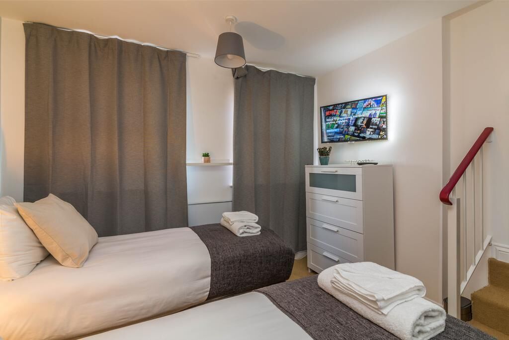 Een hotelkamer met twee bedden, een televisie aan de muur, een dressoir en een trap.