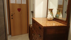 Una puerta de madera con un adorno de corazón, un aparador con encimera de mármol y dos jarrones con motivos florales.