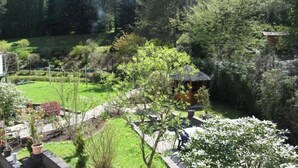 Un jardín con un pabellón, un estanque y diversas plantas y árboles.