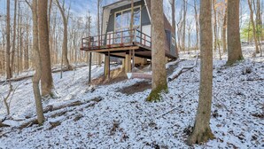 A cabin in a forest with a wooden deck and a hammock. - The Reed – A Cozy Cabin in the Woods (Rockbridge)