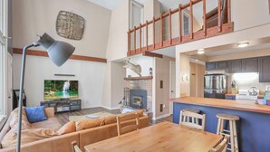 A spacious living room with a fireplace, a dining area, and a kitchen with modern appliances. - The Reed – A Cozy Cabin in the Woods (Rockbridge)