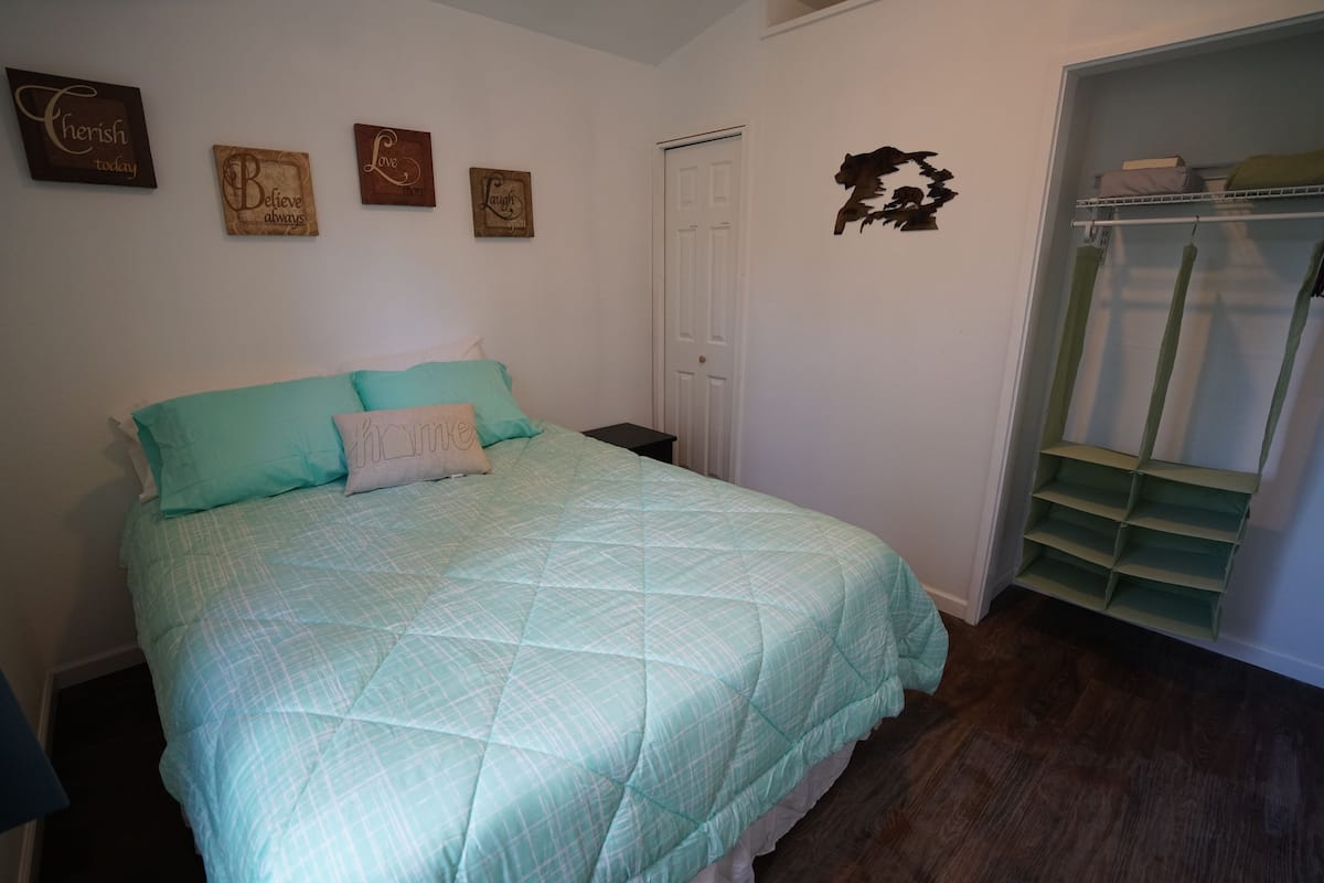 A bedroom with a bed, a closet, and a wall with motivational quotes.