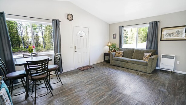 Una habitación con una mesa de comedor, sillas, un sofá y una ventana con cortinas.