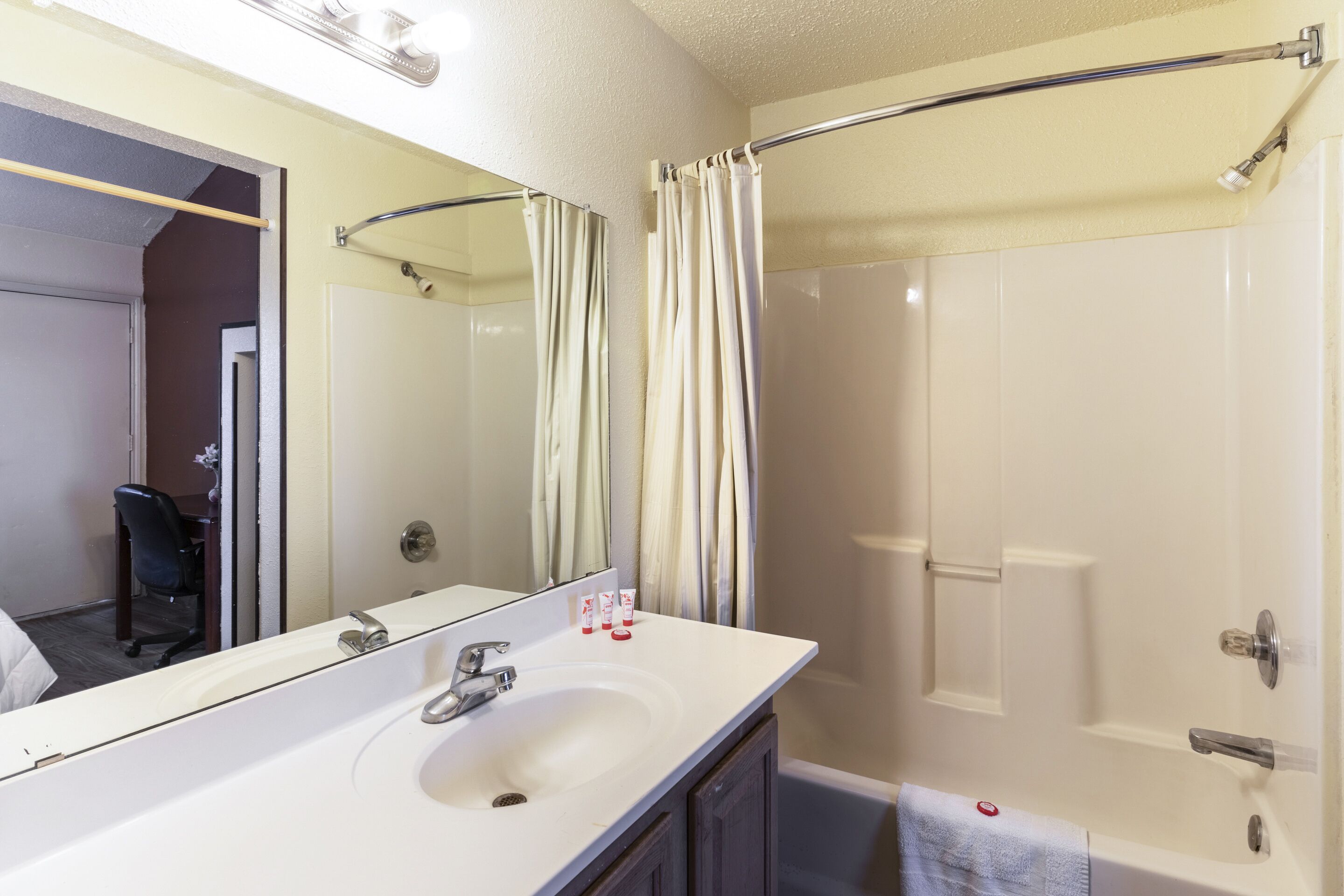 Un baño con un lavamanos blanco, un espejo, una cortina de ducha y una bañera.