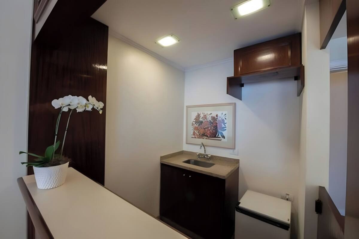 A modern bathroom with a white sink, dark cabinet, and a framed picture on the wall.