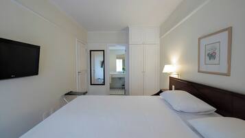 Une chambre d’hôtel avec un grand lit, un téléviseur fixé au mur, une lampe de chevet et un tableau encadré.