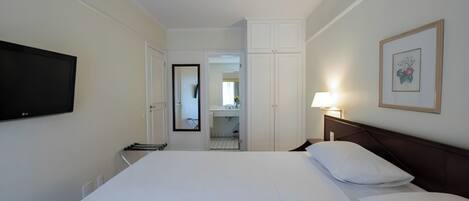 A hotel room with a large bed, a television on the wall, a bedside lamp, and a framed picture.