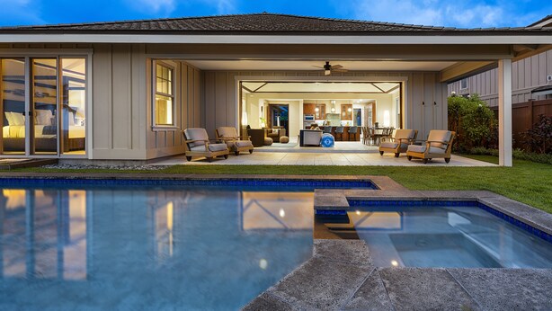 Et moderne hus med swimmingpool, udendørs møbler og en godt oplyst terrasse.