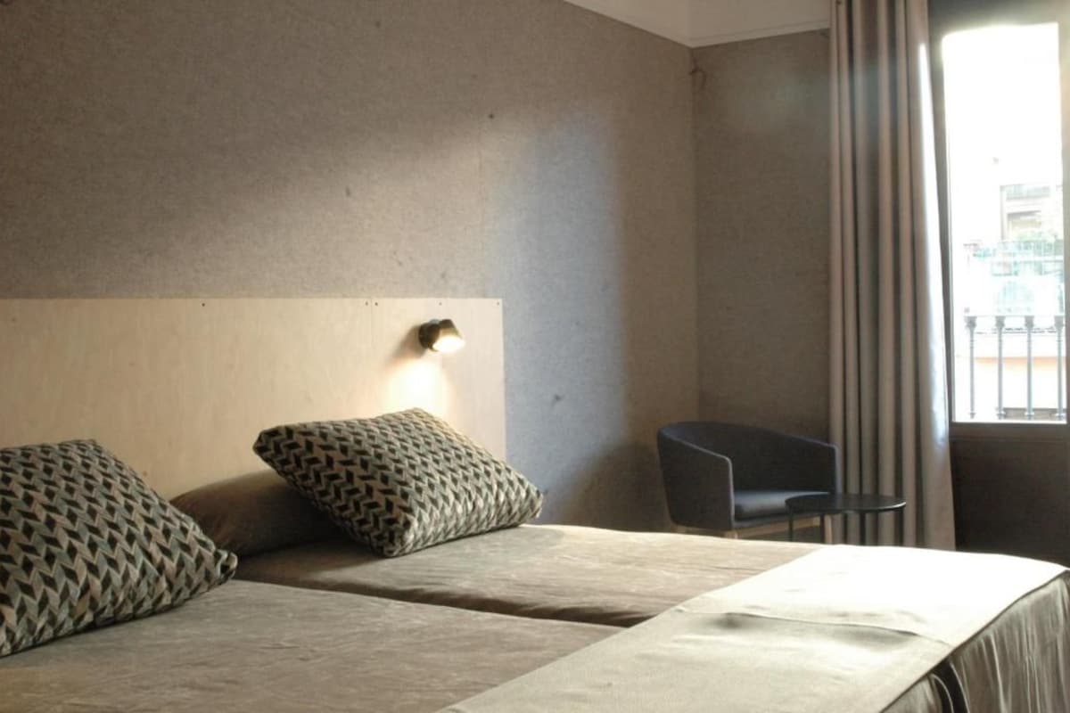 Una habitación de hotel con dos camas, una mesita y una silla.