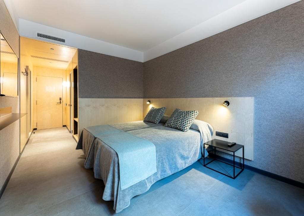 A modern bedroom with a large bed, bedside tables, and a headboard with integrated lighting.