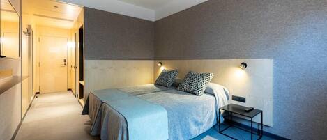 A modern bedroom with a large bed, bedside tables, and a headboard with integrated lighting.