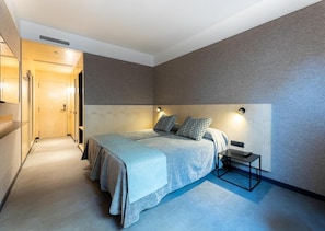 A modern bedroom with a large bed, bedside tables, and a headboard with integrated lighting. - Raval House (Barcelona)