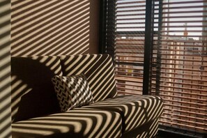 A striped sofa with a patterned pillow in a room with diagonal shadows cast by blinds. - Raval House (Barcelona)