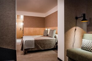 Una habitación de hotel con una cama, una mesita de noche, una lámpara y un sofá.