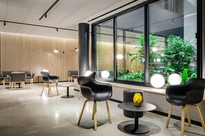 A modern interior with a seating area, large windows, and indoor plants. - Raval House (Barcelona)