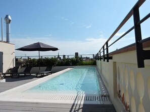 A rooftop swimming pool with lounge chairs and an umbrella. - Raval House (Barcelona)