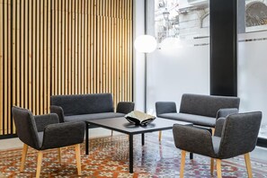 A modern interior with a wooden slat wall, a geometric patterned floor, and a table with four grey chairs. - Raval House (Barcelona)