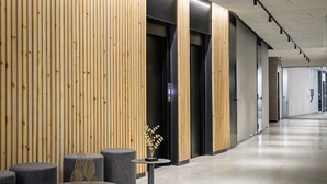 Un pasillo moderno con paneles de madera, asientos grises y un diseño limpio y minimalista.