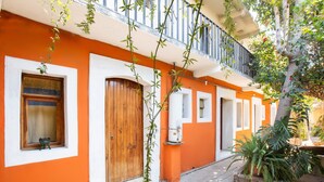 Un edificio con paredes anaranjadas, una puerta de madera y un balcón con barandilla metálica.