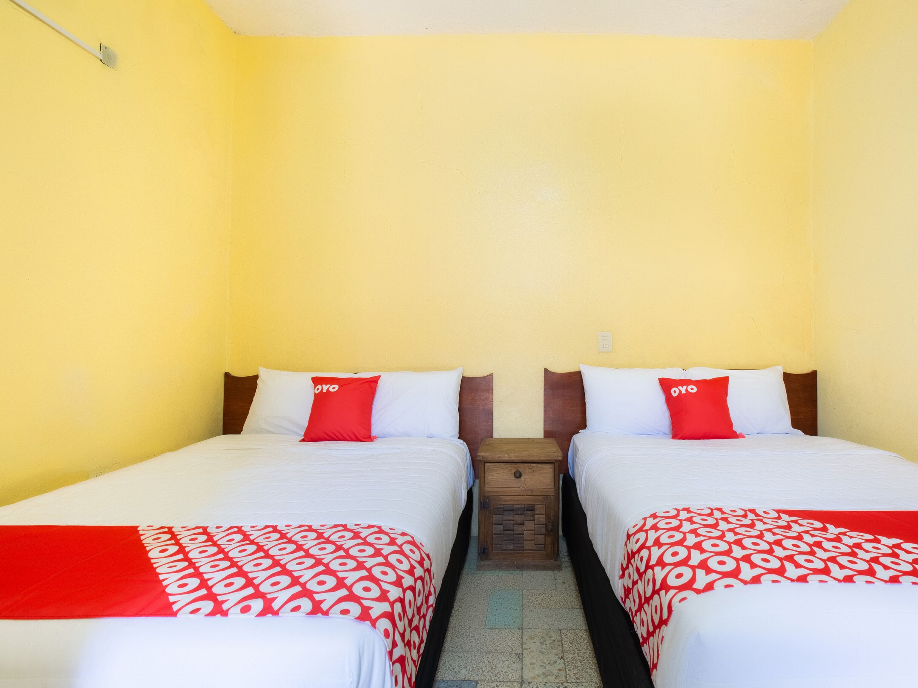 A room with two beds, each with a red and white patterned bedspread and matching pillows.